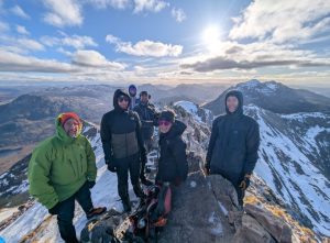 Group of hikers at the top of Spidean Coire nan Clach (Beinn Eighe,) with Liathach in the background